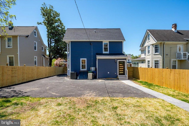 rear view of house featuring entry steps, central AC unit, a fenced backyard, and a patio area