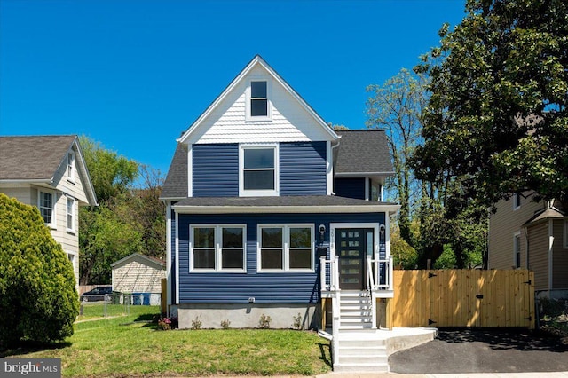 view of front of house featuring roof with shingles, fence, and a front yard