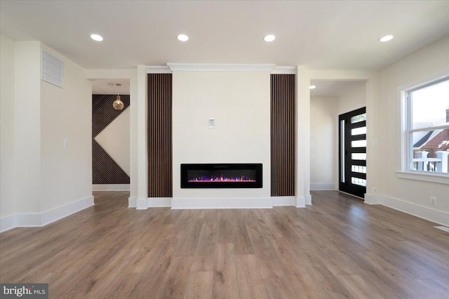 unfurnished living room with recessed lighting, visible vents, a glass covered fireplace, and wood finished floors