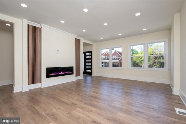 unfurnished living room with recessed lighting, baseboards, visible vents, and a glass covered fireplace
