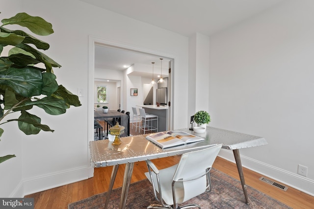 office area with baseboards, visible vents, and wood finished floors