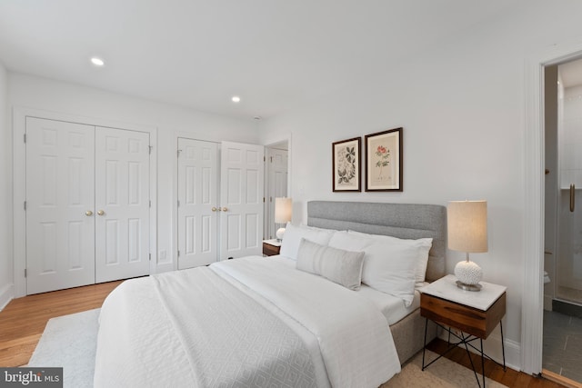 bedroom with two closets, recessed lighting, baseboards, and wood finished floors