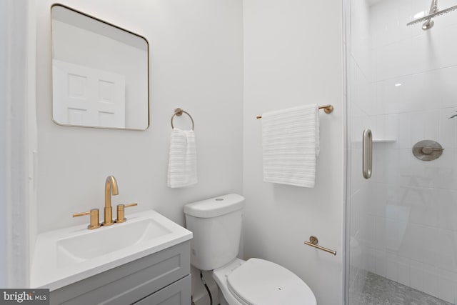 bathroom featuring vanity, a tile shower, and toilet