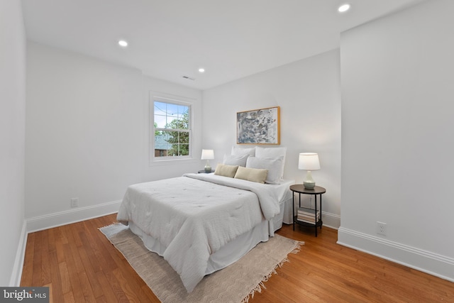 bedroom with baseboards, recessed lighting, wood finished floors, and visible vents