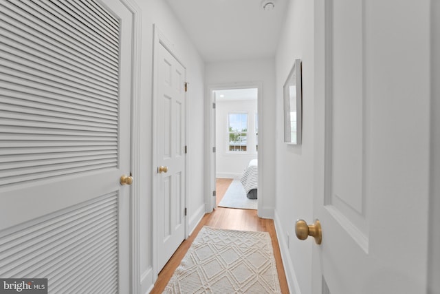corridor with light wood-style floors and baseboards