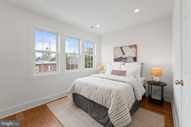bedroom featuring baseboards, recessed lighting, wood finished floors, and visible vents