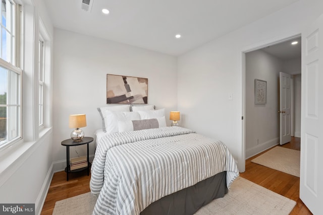 bedroom featuring multiple windows, wood finished floors, and visible vents