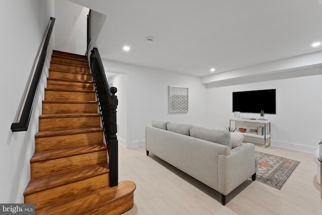 living area with recessed lighting, baseboards, light wood-type flooring, and stairs