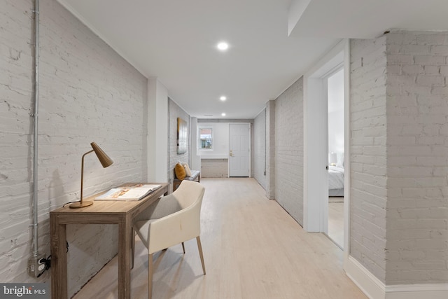 hallway with brick wall, recessed lighting, and light wood-style flooring