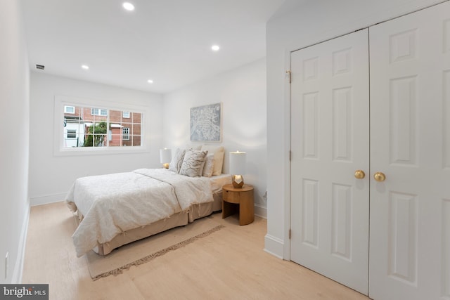 bedroom with baseboards, light wood finished floors, a closet, and recessed lighting