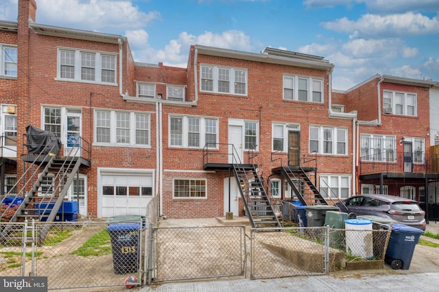 view of front of house with brick siding, a gate, stairs, and a garage