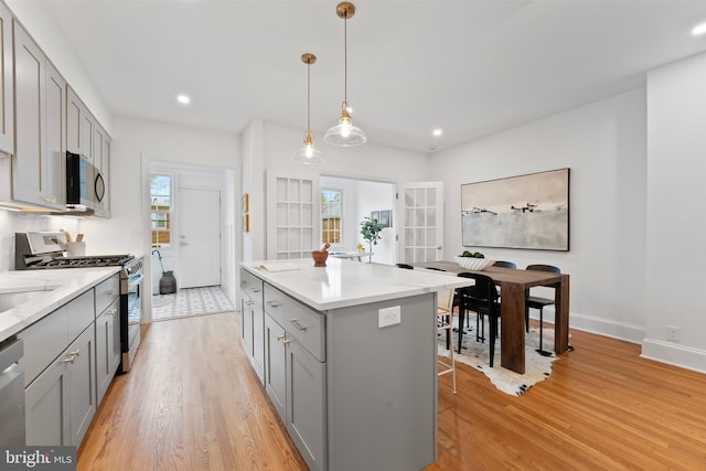 kitchen featuring appliances with stainless steel finishes, gray cabinets, and light wood-type flooring