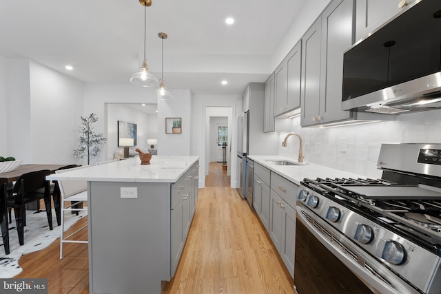 kitchen featuring a sink, gray cabinets, a kitchen island, and stainless steel appliances