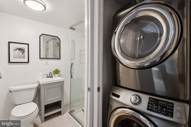 washroom with baseboards, stacked washer and dryer, and laundry area