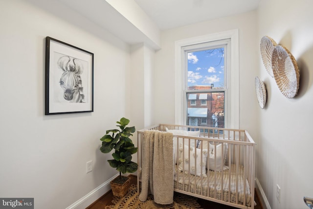 interior space with baseboards, wood finished floors, and a crib