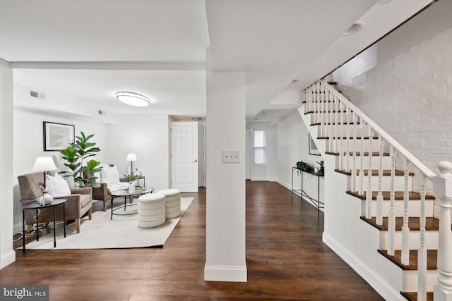 foyer featuring baseboards, visible vents, wood finished floors, and stairway