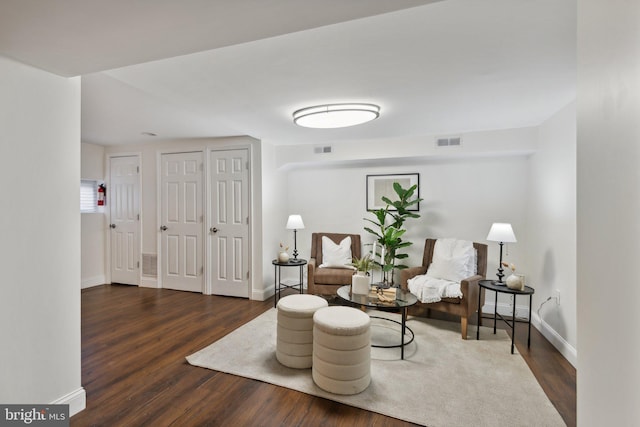living area featuring visible vents, baseboards, and wood finished floors