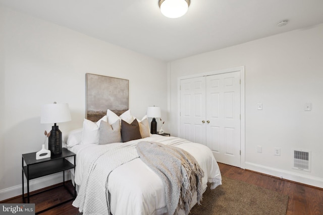 bedroom featuring baseboards, visible vents, wood finished floors, and a closet