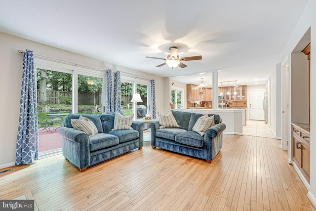 8008 Oak Hollow Ln, Fairfax Station, VA 22039 - living room with light wood finished floors, ceiling fan, baseboards, and a chandelier