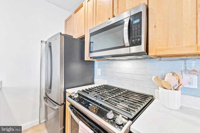 kitchen with light brown cabinetry, stainless steel appliances, decorative backsplash, and light countertops