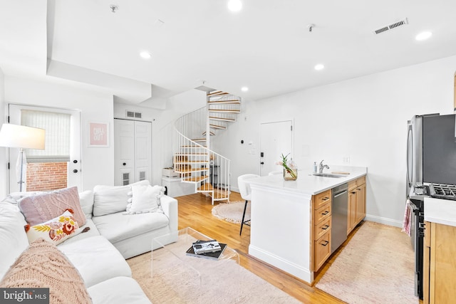 living area with visible vents, stairs, and light wood-style floors
