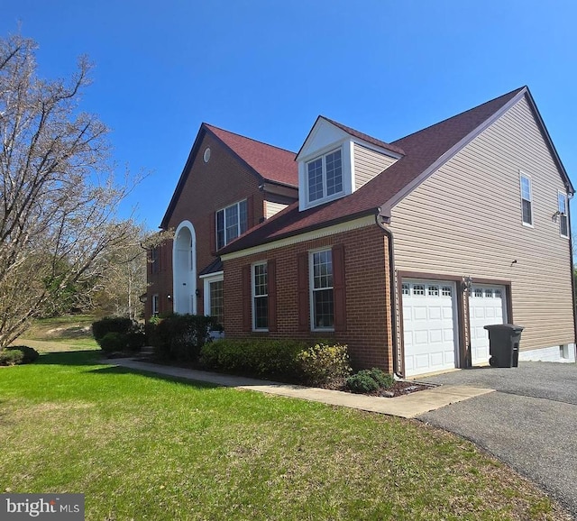 view of side of property with an attached garage, a yard, driveway, and brick siding