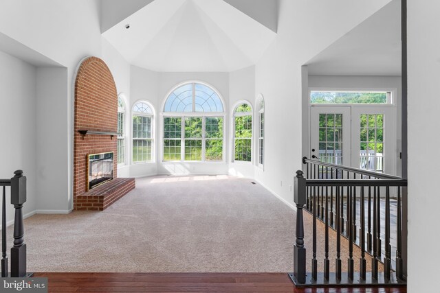 601 James Ridge Rd, Bowie, MD 20721 - unfurnished living room with baseboards, a high ceiling, a fireplace, wood finished floors, and carpet flooring