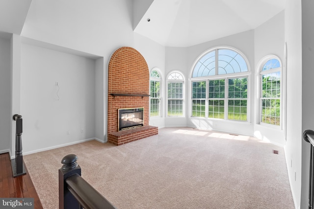 601 James Ridge Rd, Bowie, MD 20721 - unfurnished living room with high vaulted ceiling, a brick fireplace, carpet floors, baseboards, and wood finished floors