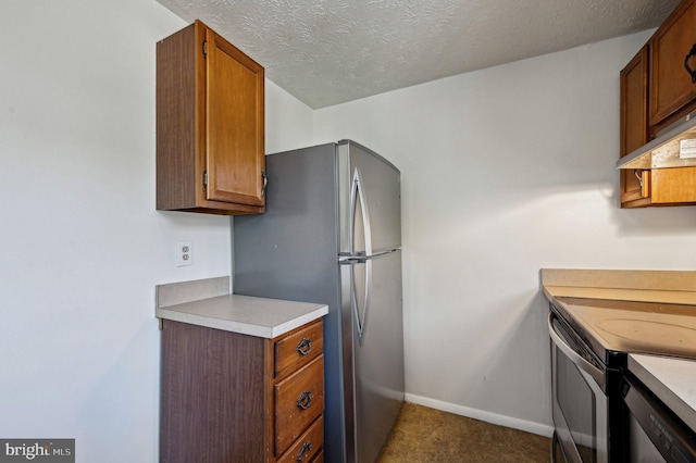kitchen featuring stainless steel appliances, light countertops, under cabinet range hood, brown cabinetry, and baseboards