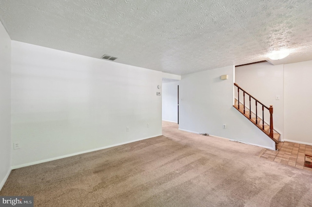 spare room featuring carpet floors, stairs, a textured ceiling, and baseboards