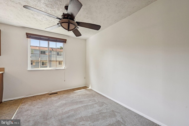 carpeted spare room with ceiling fan, a textured ceiling, and baseboards