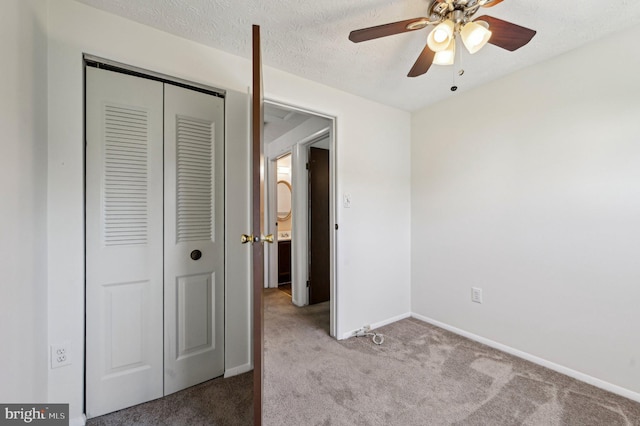 unfurnished bedroom featuring carpet flooring, a closet, baseboards, a ceiling fan, and a textured ceiling