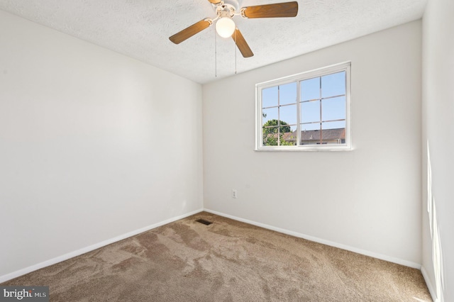 spare room featuring carpet, baseboards, a ceiling fan, and a textured ceiling