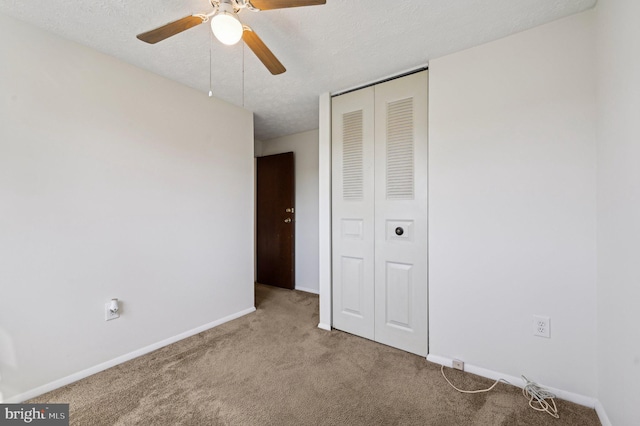 unfurnished bedroom with carpet flooring, a closet, baseboards, a textured ceiling, and a ceiling fan