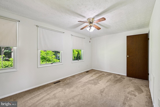 unfurnished room featuring a ceiling fan, carpet, a textured ceiling, and baseboards
