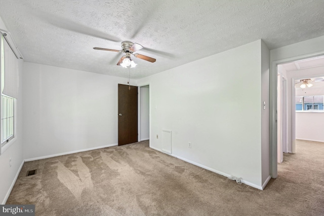 spare room with ceiling fan, carpet flooring, baseboards, a textured ceiling, and attic access