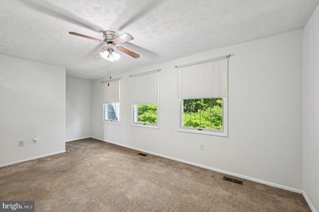 spare room with carpet, ceiling fan, baseboards, and a textured ceiling
