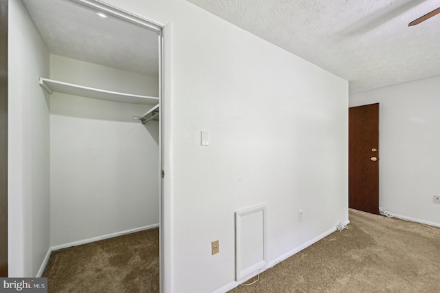 unfurnished bedroom with carpet floors, a spacious closet, a textured ceiling, baseboards, and a closet