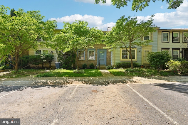view of front facade featuring uncovered parking and brick siding
