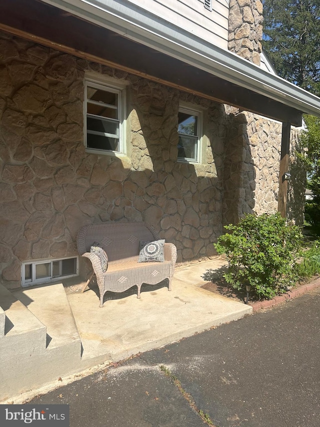 view of property exterior with stone siding, a patio, and a chimney