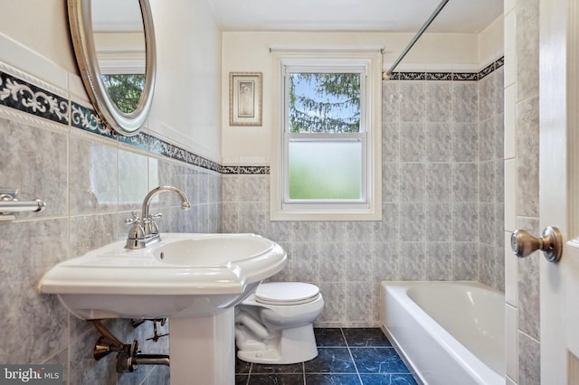 bathroom with tile patterned floors, tile walls, toilet, and shower / bathing tub combination