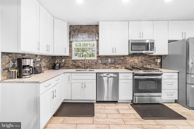 kitchen with stainless steel appliances, a sink, white cabinetry, and recessed lighting
