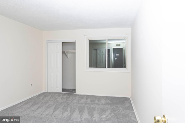 unfurnished bedroom with carpet floors, baseboards, and a closet