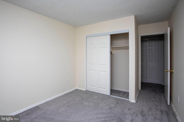 unfurnished bedroom featuring a textured ceiling, baseboards, carpet, and a closet