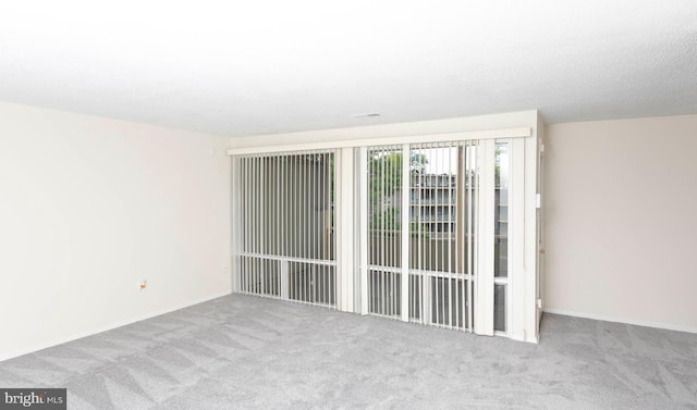 carpeted spare room featuring baseboards