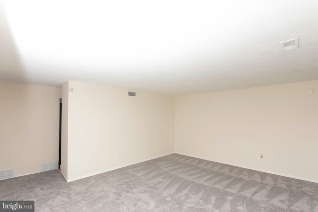 spare room featuring carpet floors, baseboards, and visible vents