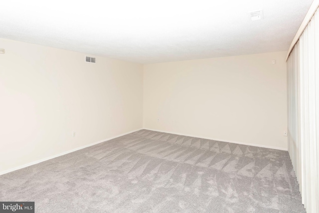 carpeted empty room featuring visible vents and baseboards