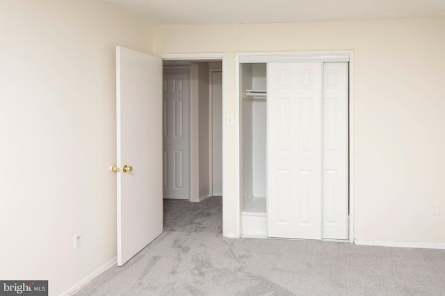 unfurnished bedroom featuring baseboards, carpet, and a closet