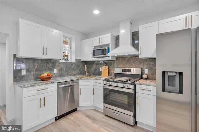1452 N Felton St, Philadelphia, PA 19151 - kitchen with wall chimney range hood, white cabinets, a sink, light wood finished floors, and stainless steel appliances