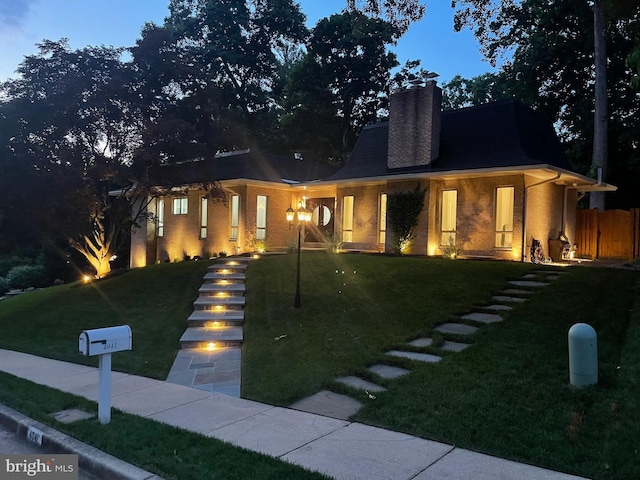 view of front of home with a chimney and brick siding